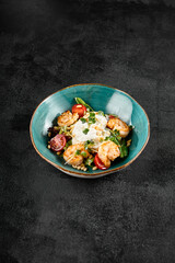 Salad with grilled shrimp and stracciatella cheese, accompanied by greens and cherry tomatoes in a turquoise bowl