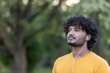 Focused indian man in sportswear with earphones enjoying music during outdoor workout