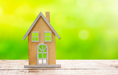 Wooden house model on wooden table with defocused green grass at background. Copy space	
