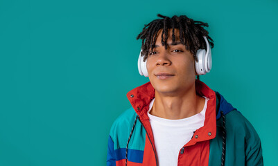 Positive young african american man listening music, enjoying headphones on blue