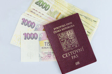 Passports of Czech Republic are stacked on white background with various denominations of CZK koruna banknotes