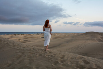 Young woman stands with her back in the sand dunes