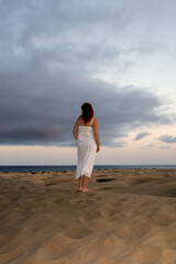 Young woman stands with her back in the sand dunes