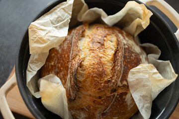 Close-up of fresh home-baked sourdough bread in cast iron pan on wooden cutting board. Bread making at home