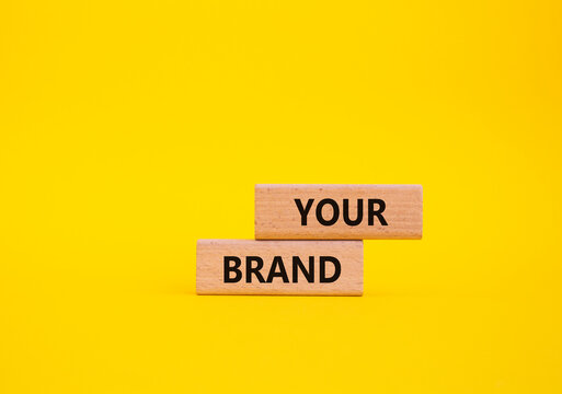 Your Brand symbol. Concept word Your Brand on wooden blocks. Beautiful yellow background. Business and Your Brand concept. Copy space