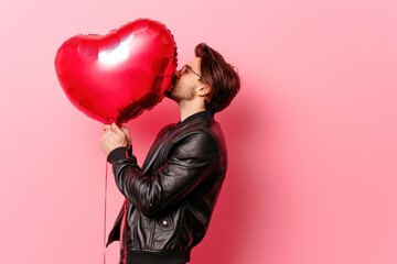 Fototapeta na wymiar Happy holding balloons shaped hearts. Valentine's day celebration, happy caucasian man on coral background. Concept of human emotions, facial expression, love, relations, romantic.