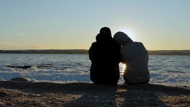 Silhouette of a couple in love on the sea at a golden and beautiful sunset in spring. 