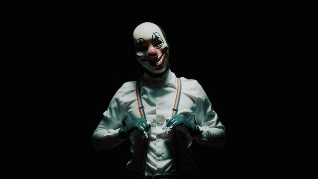 Scary clown holding his suspenders for threatening against black background