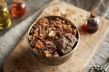 A bowl full of myrrh resin, with essential oils in the background