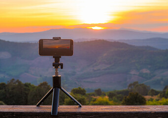 A smartphone is recording the sun setting over a mountain range.