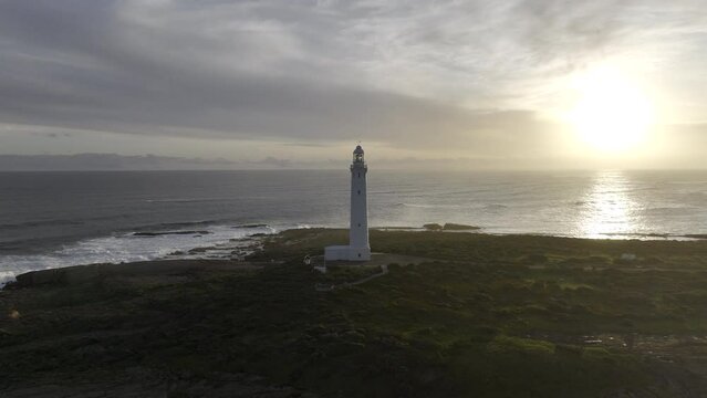 White lighthouse on Cape Leeuwin, Western Australia late afternoon. Aerial HDR ProRes drone footage orbiting left.
