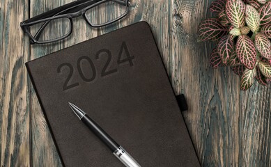 2024 year Notebook on a desk with pen and glasses