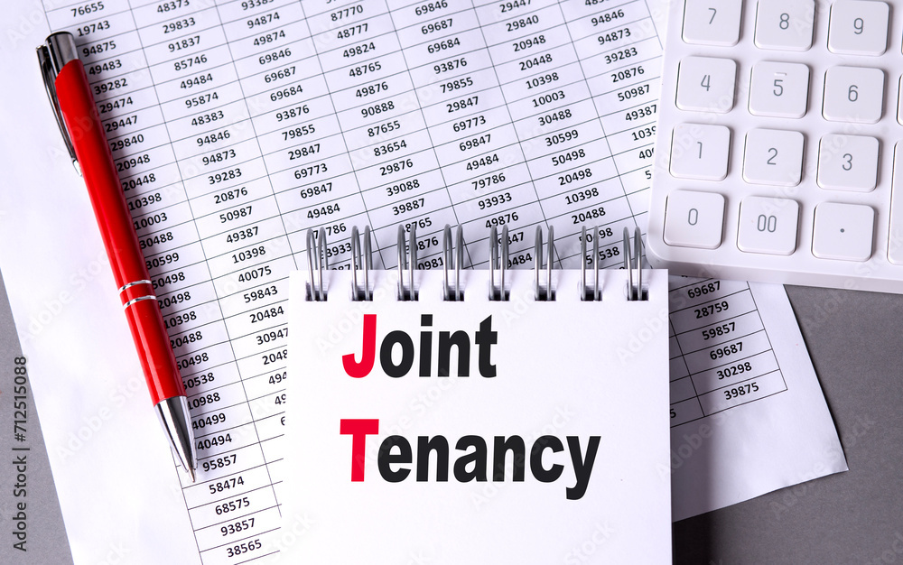 Aufkleber joint tenancy text on notebook with pen, calculator and chart on grey background