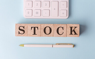 STOCK on wooden cubes with pen and calculator, financial concept