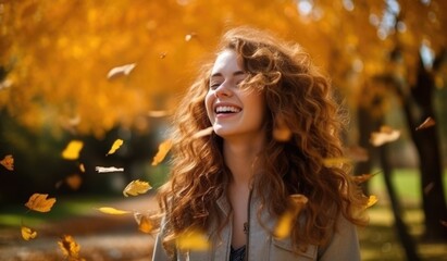 Portrait of a happy relaxed woman enjoying autumn with dry fallen leaves and sunlight in the background