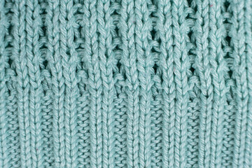 Texture and background of knitted turquoise sweater made of synthetic fabric.