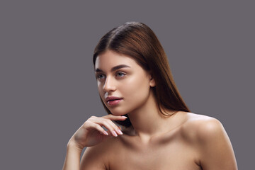 Side profile of brunette woman with sleek hair and bare shoulders, gracefully and elegantly posing...