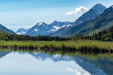 Tern Lake along Seward Highway on Kenai Peninsula in Alaska. At junction with Sterling Highway in Chugach National Forest. Mountain landscape perfectly reflected in mirror still alpine lake.