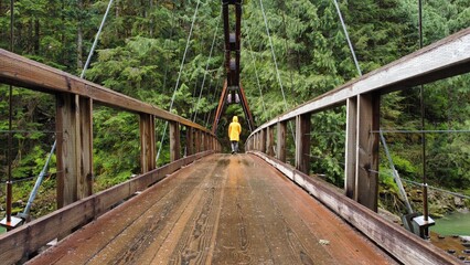 Person from behind walking on bridge in the rain
