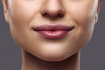 Beautiful female lips. Close-up of person's lower face featuring well-defined, plump lips with subtle natural gloss. Concept of Lip care, moisturizing and plumping cosmetic products for lips. Ad