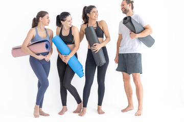 Group of happy sporty women and guy wearing body stylish sportswear holding personal carpets leaned on a white background. waiting for yoga class or body weight class. healthy lifestyle and wellness