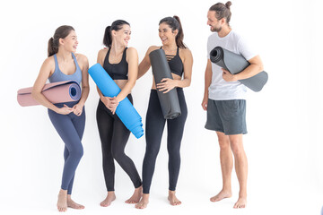 Fototapeta premium Group of happy sporty women and guy wearing body stylish sportswear holding personal carpets leaned on a white background. waiting for yoga class or body weight class. healthy lifestyle and wellness