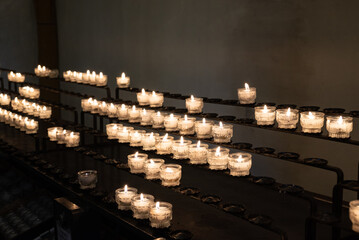 Brennende Kerzen aufgereiht als Opferkerzen auf Metallgestell in einer Kirche