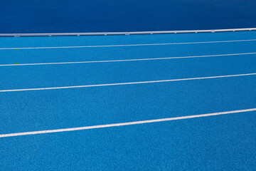 Blue Olympic track lanes with white stripes, an empty background suitable for copy space, represent the concept of physical sports and running, symbolizing commitment and pathways towards goals