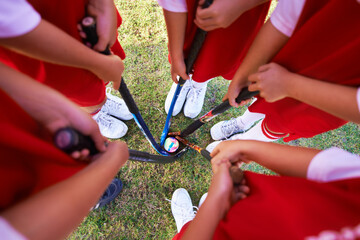 Children, hockey team and circle above with ball on green grass for sports, match or game together. Top view closeup of kids, player hands and huddle on field for teamwork or outdoor unity in nature