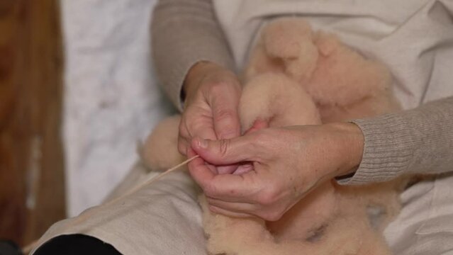 Detalle de las manos de una hilandera recogiendo lana en un ovillo.