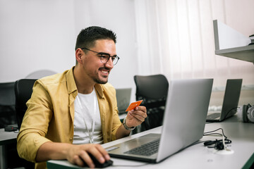 Happy cheerful smiling young adult man doing online shopping or e-shopping