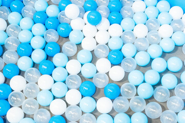 Colored plastic balls in pool of kindergarten school,White and blue plastic balls pit in game room,Many white balls background. - obrazy, fototapety, plakaty