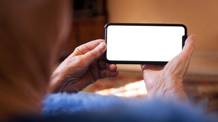 Old woman at home using a mobile phone with white screen. Mockup device