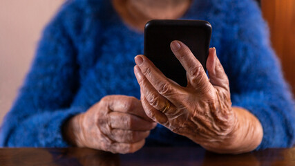 Elderly woman using a mobile phone over wood table at living room of home.