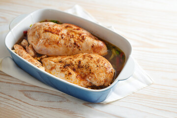 Chicken breast fillet, seasoned with paprika, pepper and salt on a bed of vegetables and broth in a casserole, prepared for braising in the oven, cooking at home, copy space