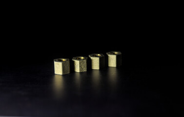 Four brass nuts on dark background