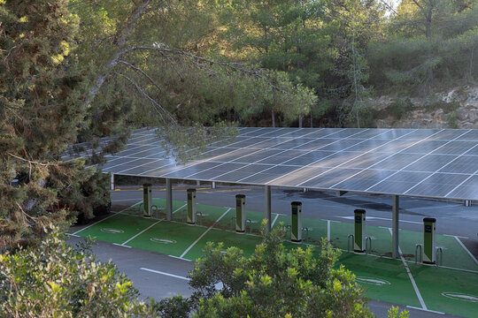A spacious parking lot equipped with multiple solar panel canopies providing power to a row of electric vehicle charging stations