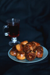 Plate of homemade cinnamon rolls and cup of tea. Dark background, selective focus.