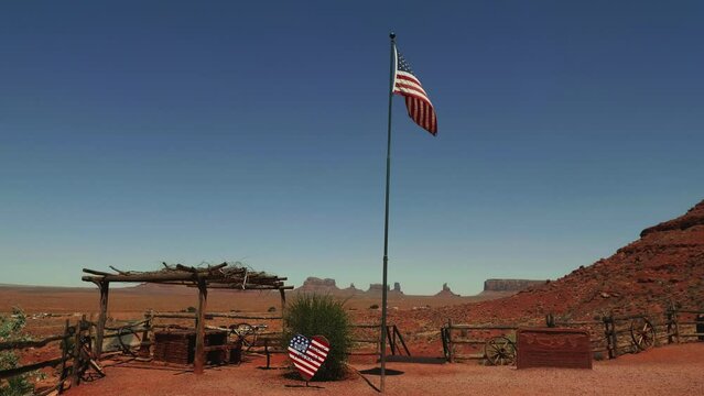 Beautiful scenic view of American flag waving in Wild West museum with old wooden relics in the middle of hot desert.