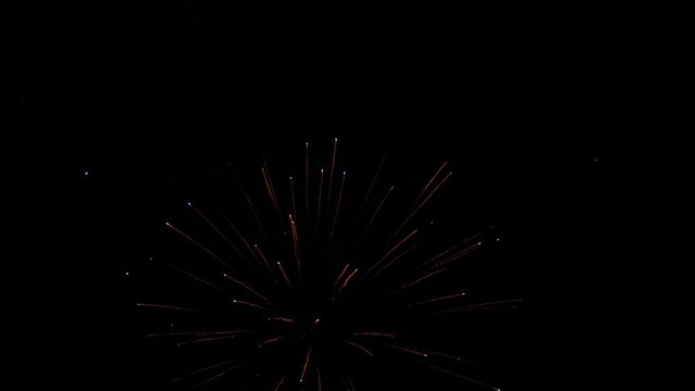 Breathtaking fireworks bursts in black night sky on holiday. Dazzling display with burning firework traces against darkness during performance. Fireworks amuse holiday event audience in dark night