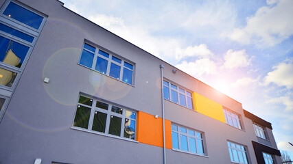 Multi-colored facades of the school with white window frames. - obrazy, fototapety, plakaty