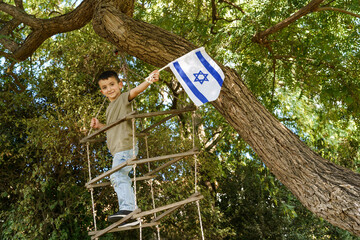 Smiling Child On A Rope Ladder, Placing An Israeli Flag On A Tree.