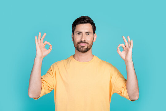 Portrait photo of brunet hair handsome man wearing yellow t shirt demonstrate alright symbol double okey isolated on cyan color background
