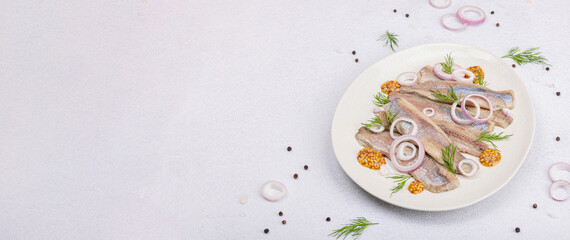 Salted herring with dijon mustard, dill and red onion rings. Marinated filleted fish on light stone