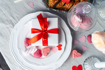 Creative table setting with gift and desserts for valentine day. Top view