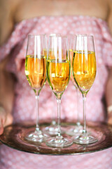 Young woman with champagne glasses on tray