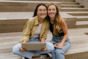 two young pretty women sitting in student campus co-working outside