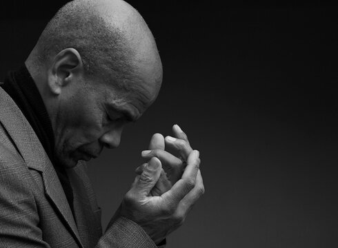 man praying to god Caribbean man praying with black grey background with people stock image stock photo	