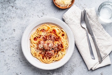 Spaghetti with meatballs, tomato sauce and parmesan on gray background