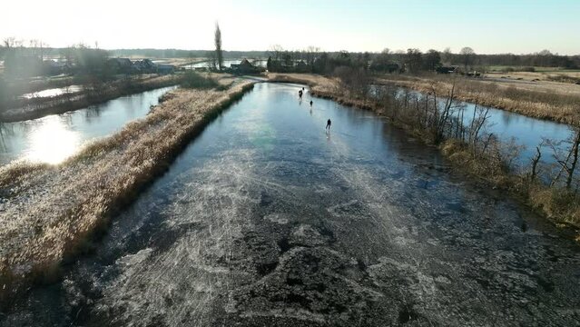 Ice skating on a frozen lake in the Weerribben Wieden nature reserve seen from above during a cold winter day in The Netherlands.